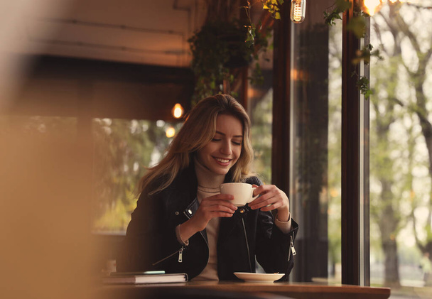 Young woman with cup of coffee at cafe in morning - Photo, image