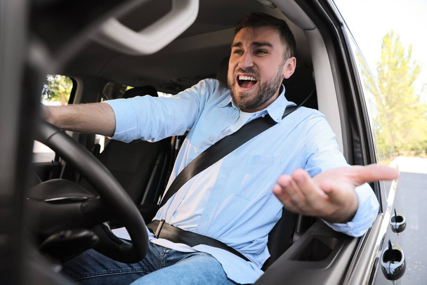 Emotional man in car. Aggressive driving behavior - Фото, зображення