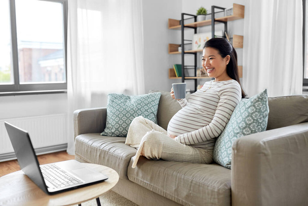 happy pregnant asian woman with laptop at home - Foto, Imagem