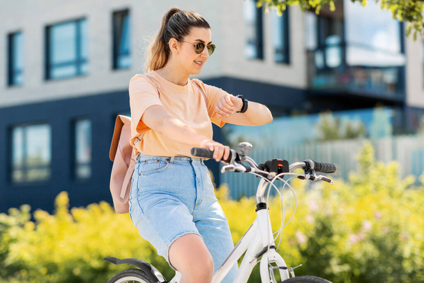 woman with smart watch riding bicycle in city - Φωτογραφία, εικόνα