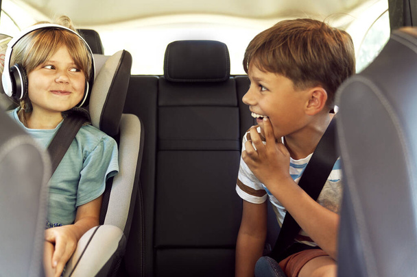 Happy siblings on rear seat of car                                - Foto, afbeelding