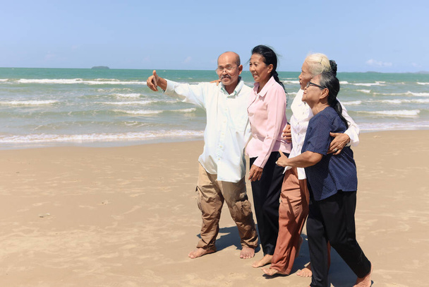 4人の高齢者の高齢者の友人のグループは、屋外に一緒に旅行し、携帯電話で自撮りをし、砂のビーチで楽しい時間を過ごし、休暇中に休息し、リラックスしてください。. - 写真・画像