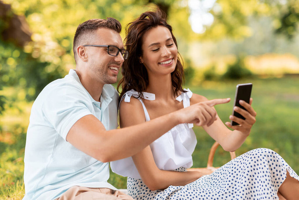 happy couple with smartphone at picnic in park - Valokuva, kuva
