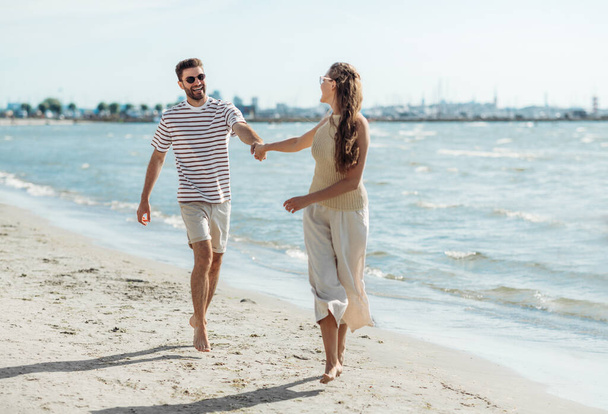 happy couple running along summer beach - Foto, afbeelding