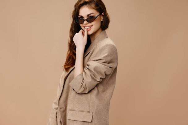 donna affascinante in cappotto beige e occhiali sorridono gesticolando con le mani - Foto, immagini