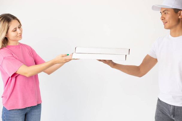 The delivery man gives the pizza to the client. - Фото, изображение