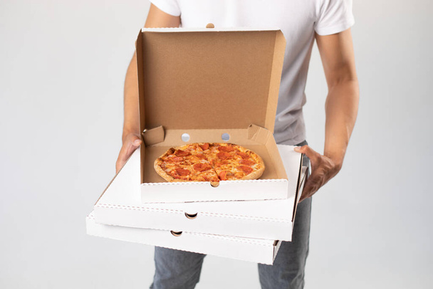 Asian delivery man in white cap and t-shirt holds boxes of pizza. Mock-up. - Фото, изображение