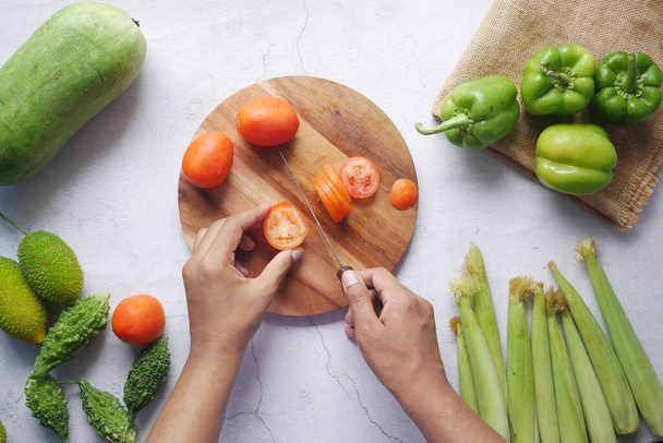 Hand van de persoon snijden tomaten op snijplank  - Foto, afbeelding