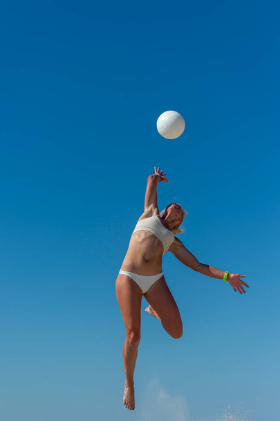 Девушка играет в волейбол на пляже. Концепция профессионального спорта - Фото, изображение