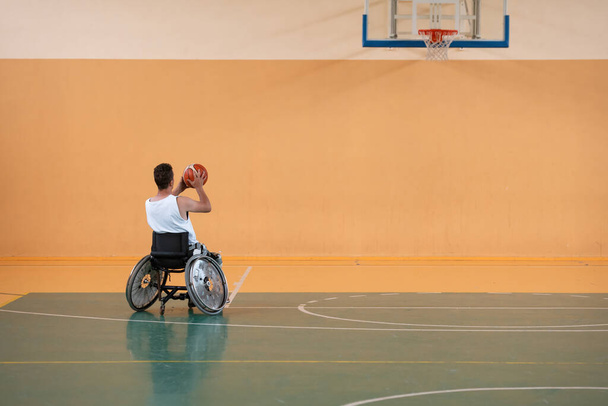 una foto di un veterano di guerra che gioca a basket con una squadra in una moderna arena sportiva. Il concetto di sport per i disabili - Foto, immagini