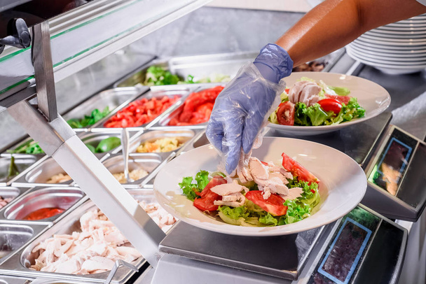 Chef prepares salad at the salad bar. Salad making process. Showcase salad bar with an assortment of ingredients for healthy and dietary food - Foto, Imagem