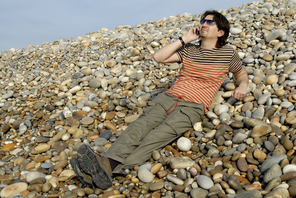 A fiatalember a tengerparton a mobiltelefon - Fotó, kép