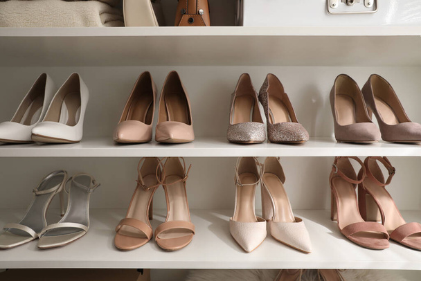 Different stylish women's shoes on shelving unit - Fotó, kép