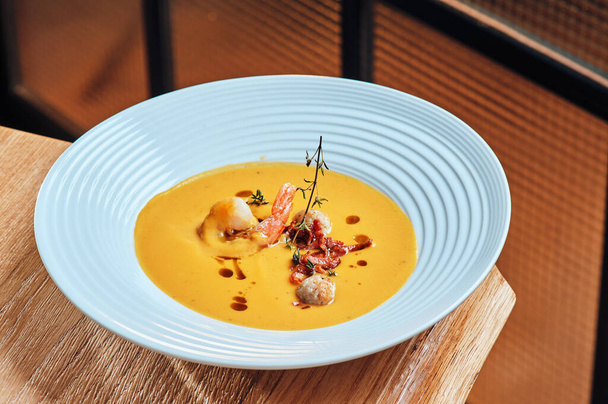 Tökkrém leves sült garnélával, gyönyörű tányéron, fából készült háttérrel. Egészséges bio étel koncepció. A szöveg helye - Fotó, kép