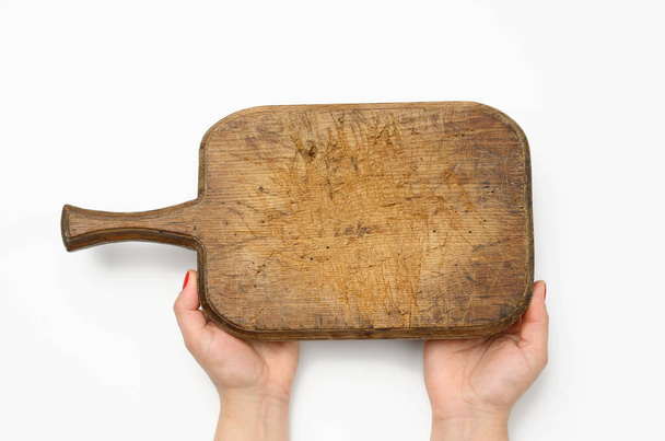 female hand with red manicure holds blank old vintage rectangular kitchen chopping board on white background - Fotó, kép