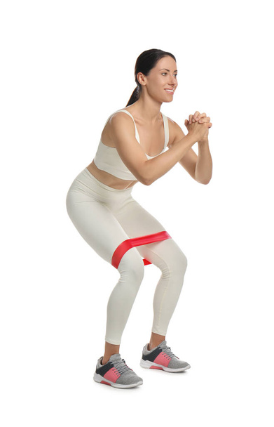 Woman doing squats with fitness elastic band on white background - Photo, image