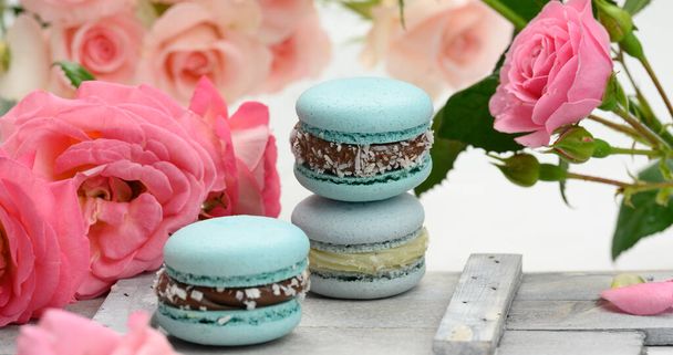 stack of blue macarons on a white table and pink rosebuds, delicious dessert, close up - Φωτογραφία, εικόνα