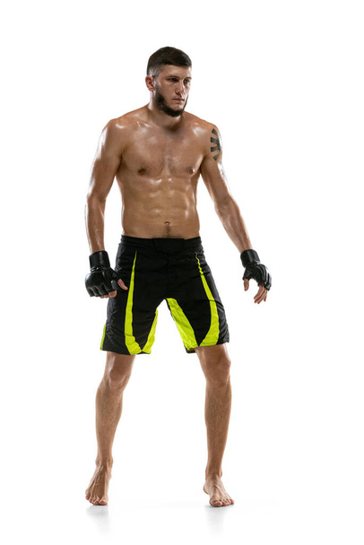 Full-length portrait of Caucasian athlete, professional male MMA boxer isolated on white studio background. Sport, competition and human emotions concept. - Photo, Image