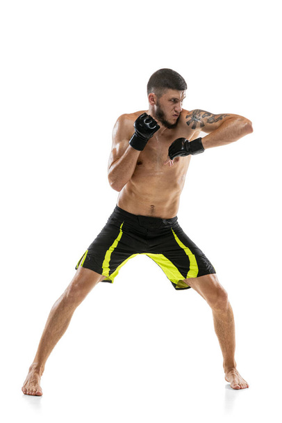 Un hombre, boxeador profesional masculino MMA en movimiento aislado sobre fondo blanco del estudio. Ajuste muscular caucásico atleta lucha. - Foto, imagen