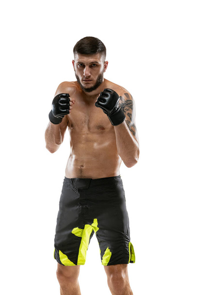 Portrait of professional male MMA boxer practicing isolated on white studio background. Fit muscular caucasian athlete fighting. - 写真・画像
