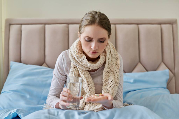 Sick woman with glass of water and pills in her hand - Foto, Bild