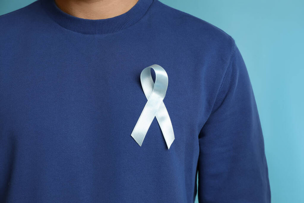 Man with ribbon on light blue background, closeup. Urology cancer awareness - Φωτογραφία, εικόνα