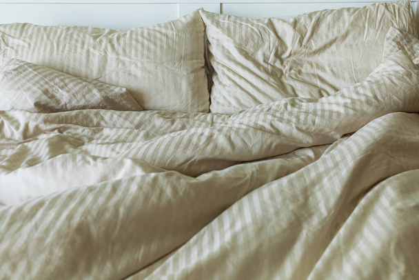 An unmade bed with pillows, sheets, and a blanket,  front vew - Photo, Image