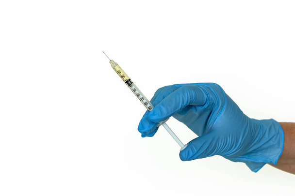 A blue-gloved woman`s hand holds a syringe, isolated - Photo, Image