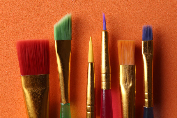 Set of different paintbrushes on orange background, flat lay - 写真・画像