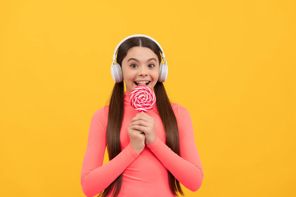 lollipop child. kid in headphones hold lollypop. sugar candy on stick. caramel candy shop. - Photo, Image