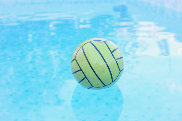 πράσινη λαστιχένια μπάλα που επιπλέει σε μια πισίνα με τυρκουάζ νερά - Φωτογραφία, εικόνα
