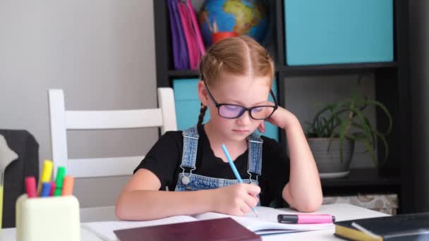 Menina ruiva caucasiana grave com óculos estudando em casa, fazer lição de casa - Filmagem, Vídeo