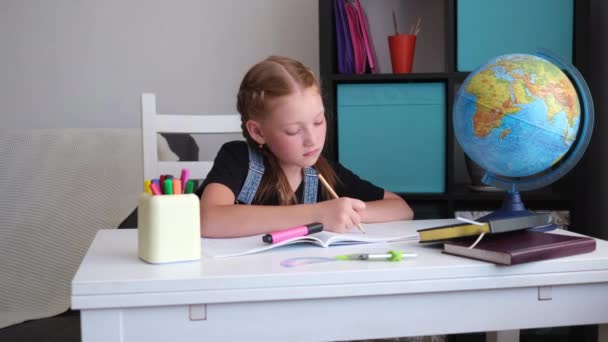 Poważny biały ruda dziewczyna uczy się w domu, zrobić pracę domową - Materiał filmowy, wideo