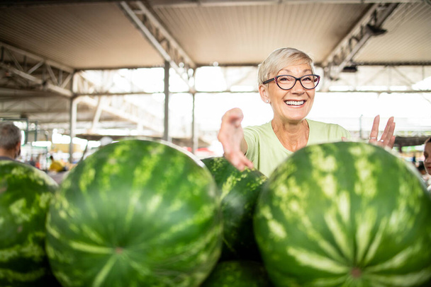 Portrét starší ženy prodávající na trhu čerstvé organické melouny. - Fotografie, Obrázek