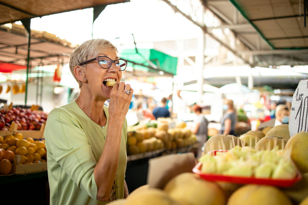 Portrét starší ženy kupující čerstvý organický meloun na trhu pro zdravou výživu. - Fotografie, Obrázek
