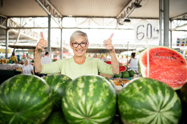 Portrét starší ženy prodávající na trhu čerstvé organické melouny. - Fotografie, Obrázek