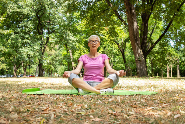 高齢者の白人女性瞑想とヨガの練習を行う. - 写真・画像