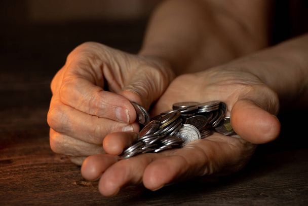 egy öregasszony kezei, fillérekkel az asztalon, pénz egy nyugdíjas kezében. - Fotó, kép