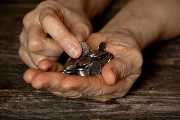 egy öregasszony kezei, fillérekkel az asztalon, pénz egy nyugdíjas kezében. - Fotó, kép