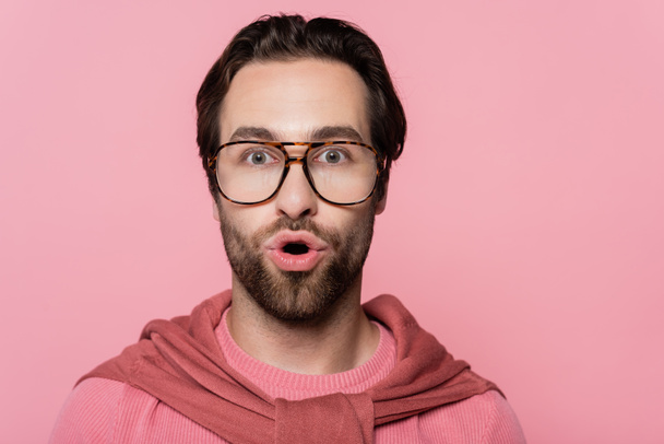 Amazed man in eyeglasses looking at camera isolated on pink  - Фото, зображення