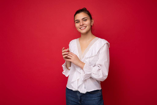 Portrait of positive cheerful fashionable woman in formalwear holding two hands together looking at camera isolated on red background with copy and empty space - Fotó, kép
