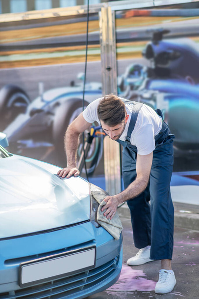 Mężczyzna wycieranie reflektora samochodu w myjni samochodowej - Zdjęcie, obraz