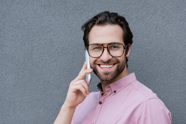Smiling businessman in eyeglasses talking on smartphone outdoors  - Foto, Imagem