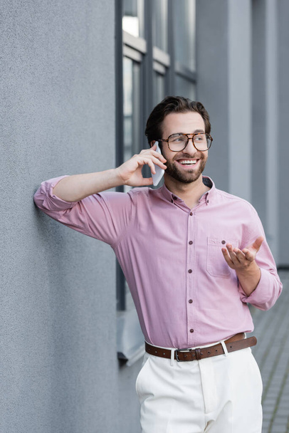 Happy manager in formal wear talking on mobile phone near building  - Φωτογραφία, εικόνα