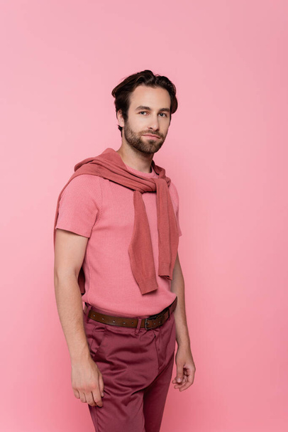 Young man with jumper on shoulders looking at camera isolated on pink - Foto, immagini
