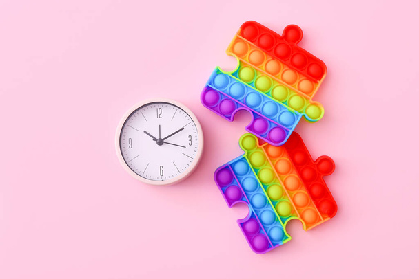 Πολύχρωμα antistress αισθητήρια παιχνίδια με ρολόι σε ροζ φόντο, top view - Φωτογραφία, εικόνα