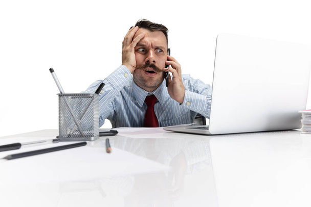 One young Caucasian man, office worker looking at laptop screen on white background. Looks upset, funky - Photo, Image