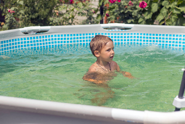 A criança nada e ri na piscina de molduras. Dia ensolarado de verão. Água da piscina azul e morna - Foto, Imagem