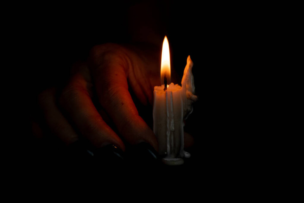 mão feminina no escuro perto da vela, chama de vela à noite, religião - Foto, Imagem