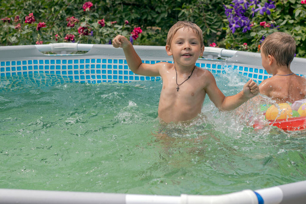 子供はフレームプールで泳いで笑います。夏の晴れた日。青と暖かいプールの水. - 写真・画像